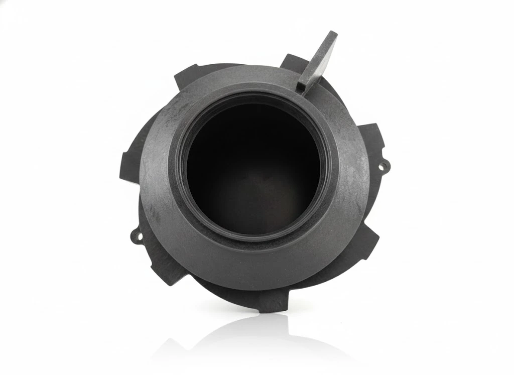 Conector de plástico negro con forma circular y rosca en el borde, utilizado en sistemas hidráulicos.