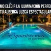 Alberca residencial iluminada de noche con luces LED azul turquesa, cascada decorativa y logo de Aquasistemas de Querétaro en el fondo.